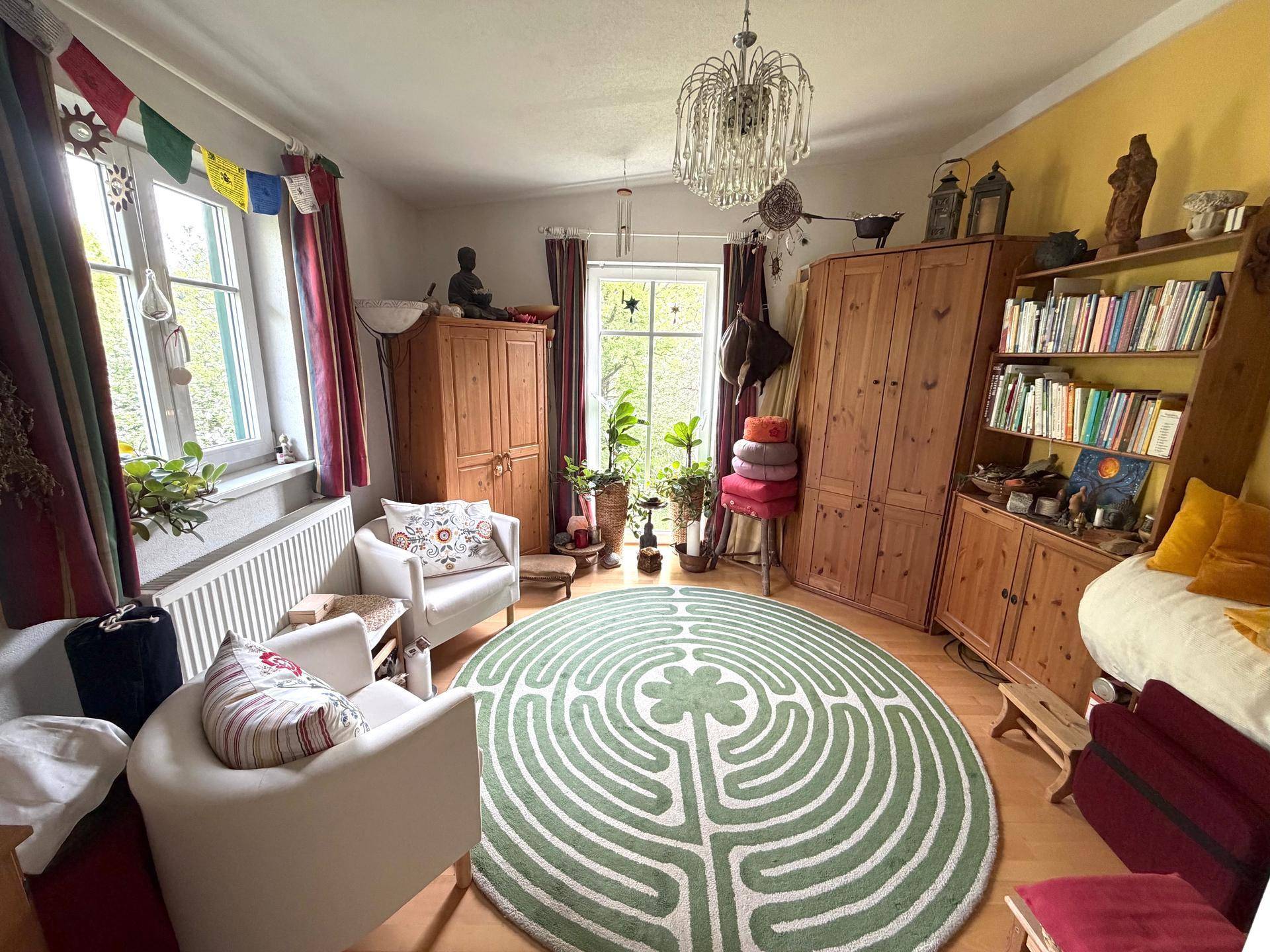 Farbenfroher Wohnraum mit Holzboden, Bücherregal und dekorativem Teppich.