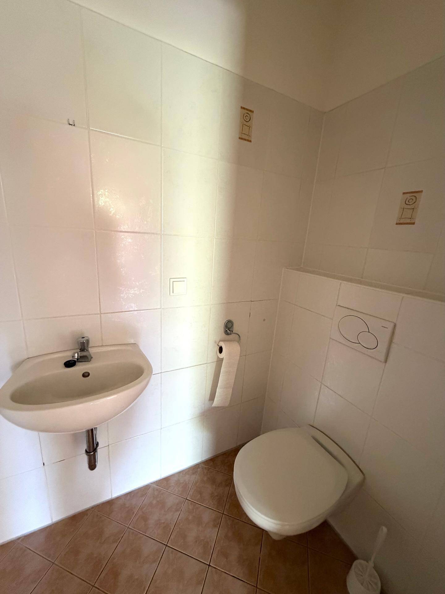 Kleines Gäste-WC mit Wand-WC, Waschbecken und hellen Fliesen in gutem Zustand.