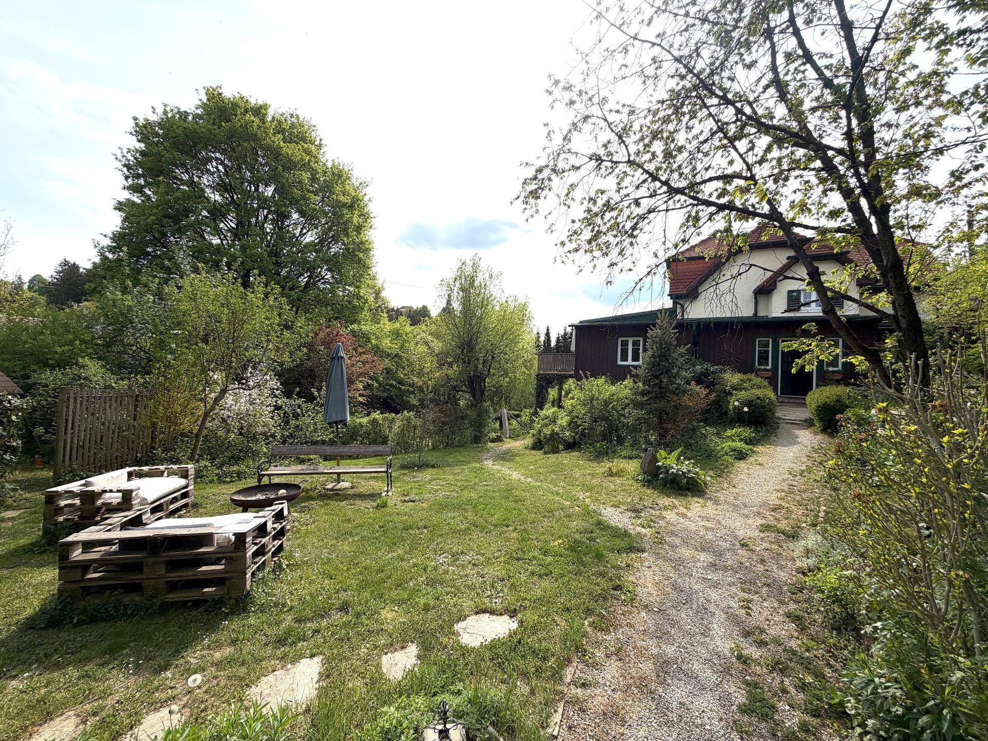 Weitläufiger Garten mit Sitzgelegenheiten und Blick auf das charmante Landhaus im Hintergrund.
