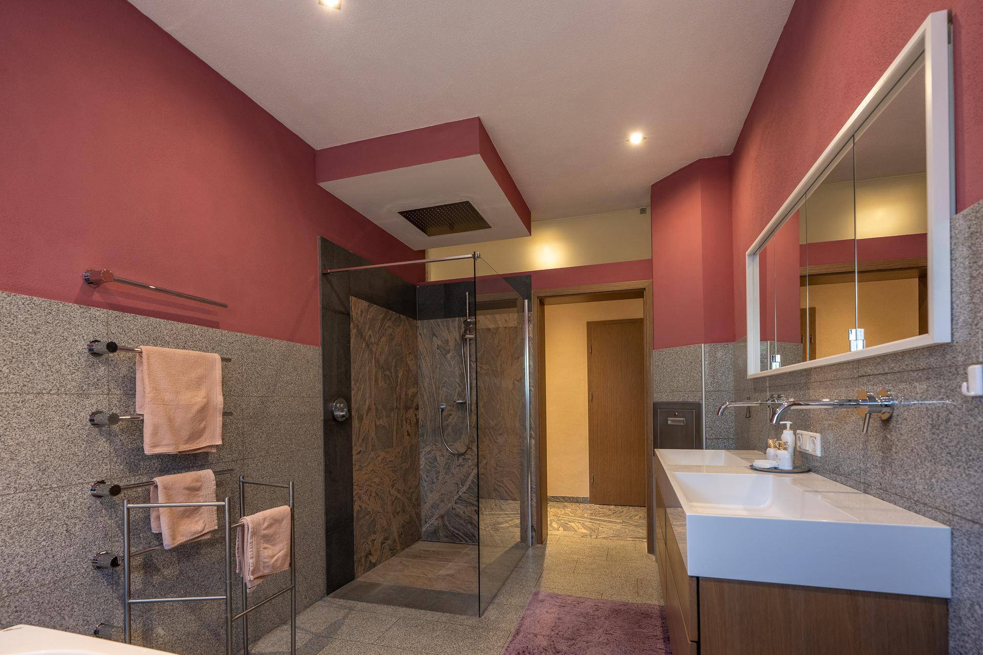 Modernes Badezimmer mit großer begehbarer Dusche, Doppelwaschbecken und beheiztem Handtuchhalter.