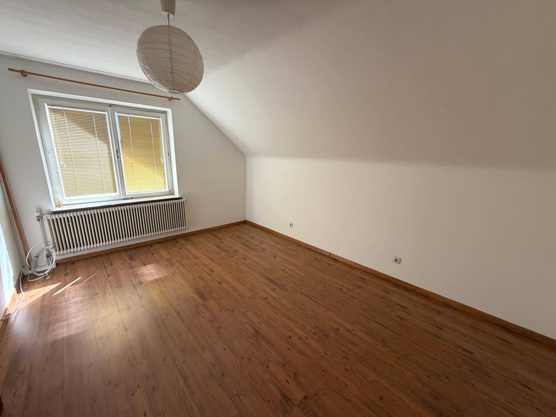 Gemütliches Schlafzimmer im Dachgeschoss mit Holzboden, viel Tageslicht und Heizung.