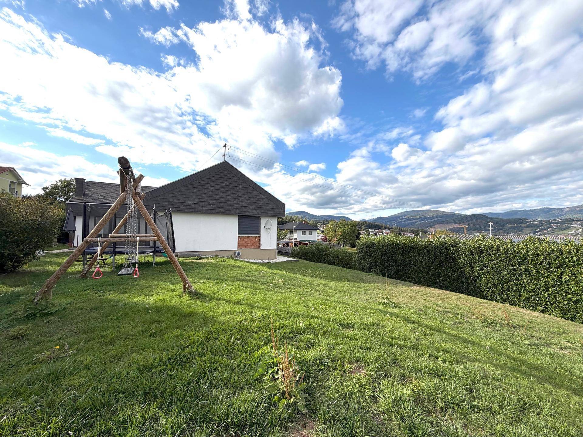 Großer grüner Garten mit Schaukel und weitem Blick auf die umliegende Landschaft.