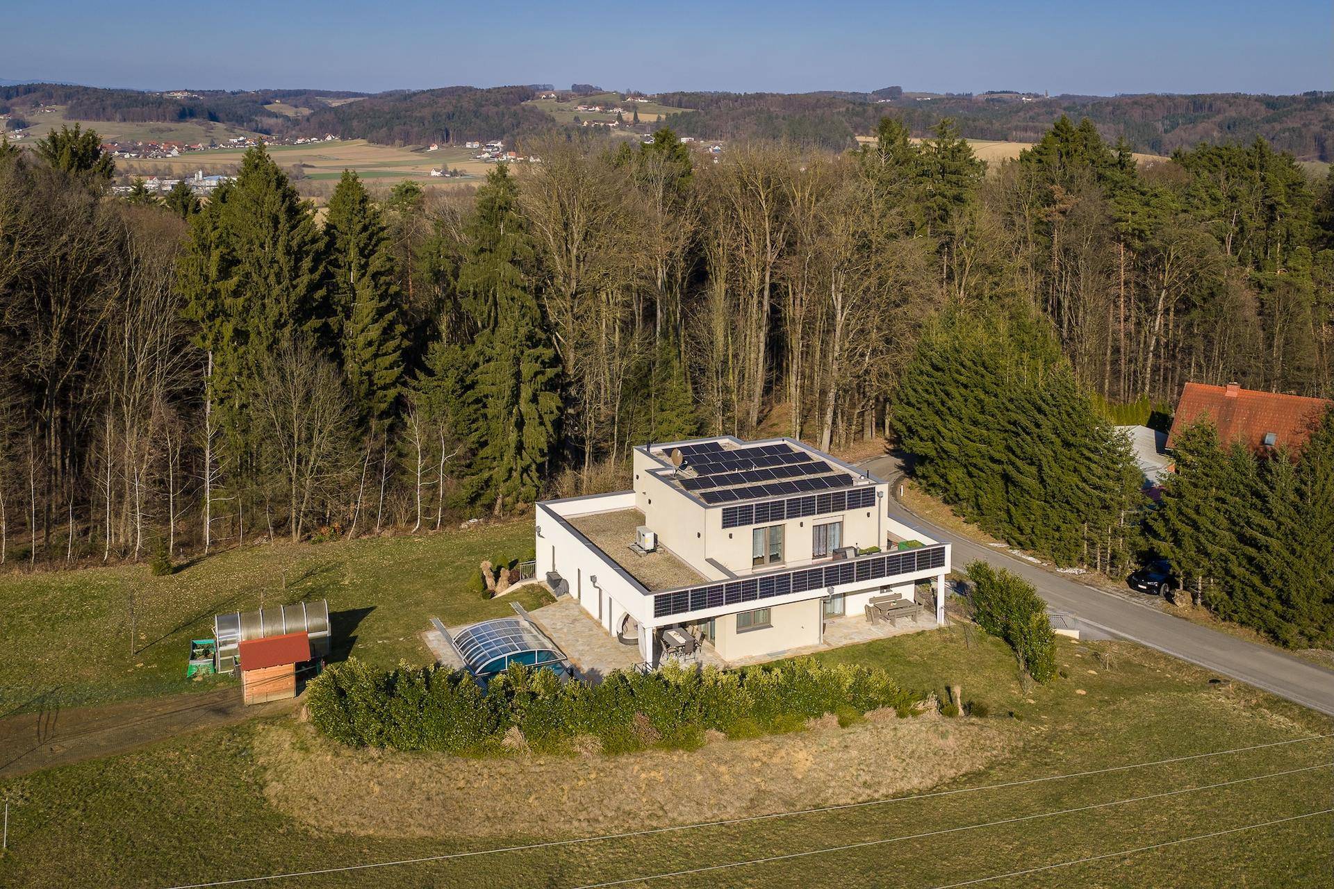 Luftaufnahme der modernen Villa mit Photovoltaikanlage, Pool und weitem Blick über die Landschaft.