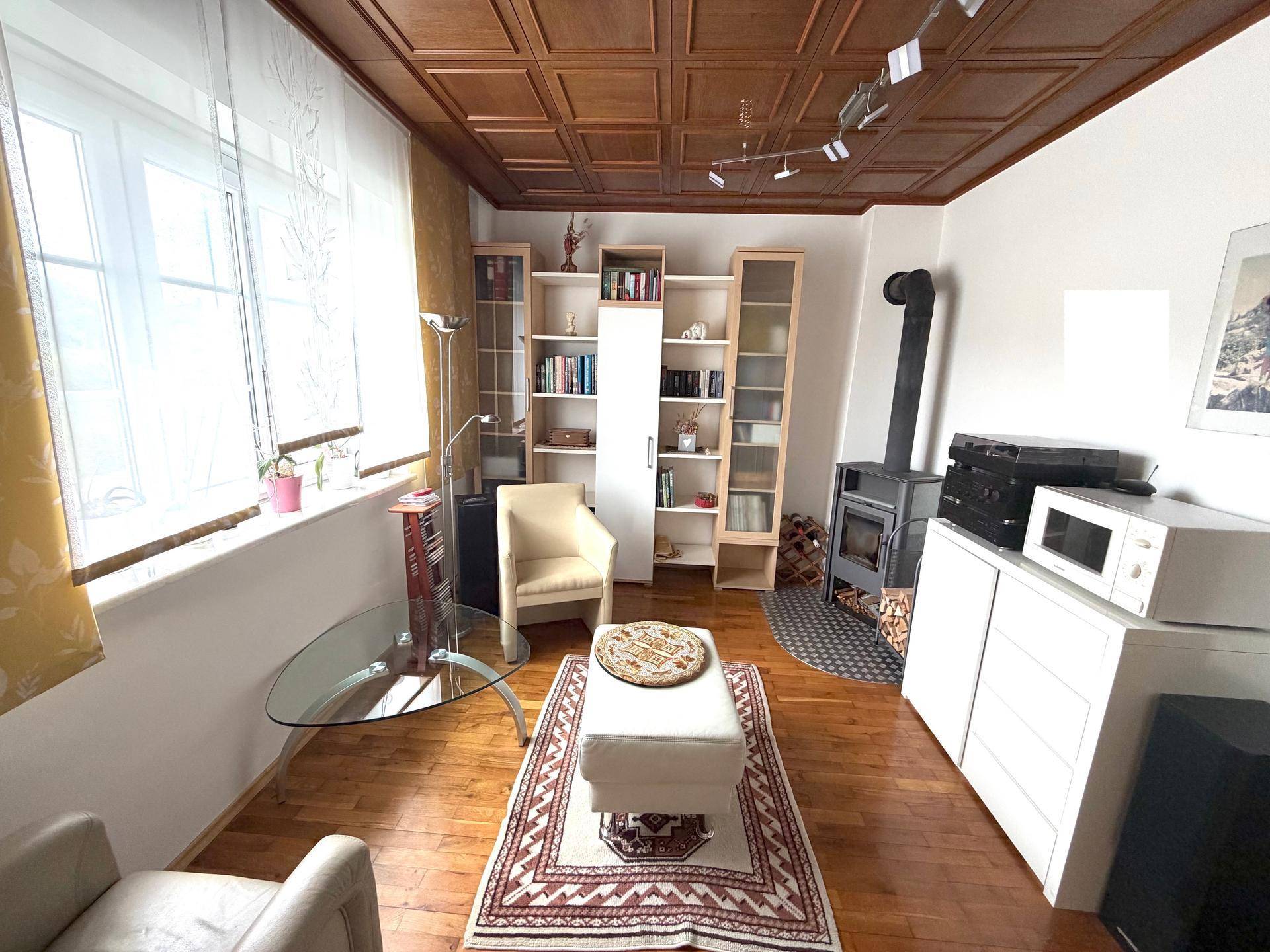 Helles Wohnzimmer mit Holzdecke, Kaminofen und Holzboden, ideal für gemütliche Abende.
