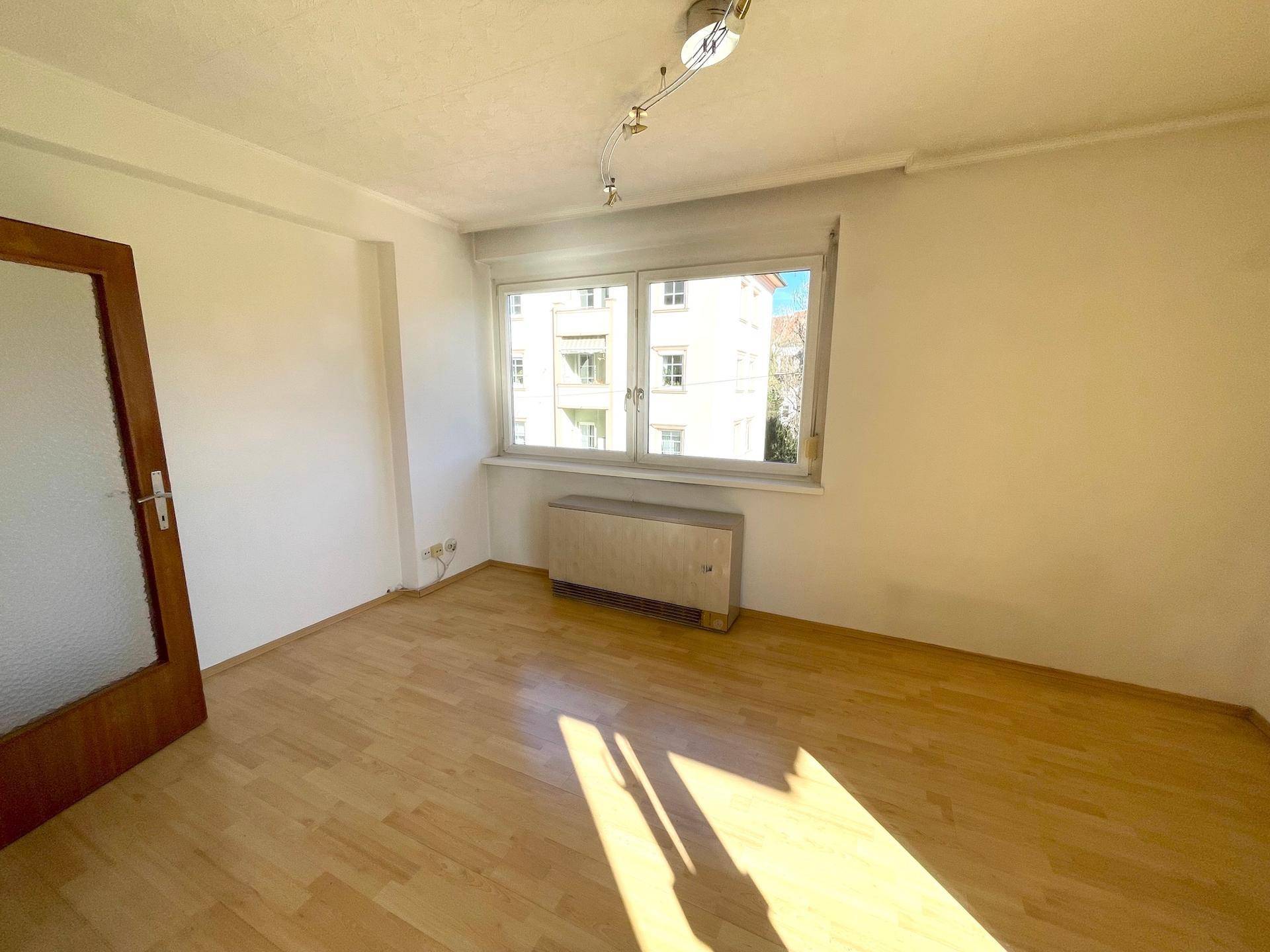 Ruhiges Zimmer mit Parkettboden und großem Fenster, ideal als Schlaf- oder Arbeitszimmer.