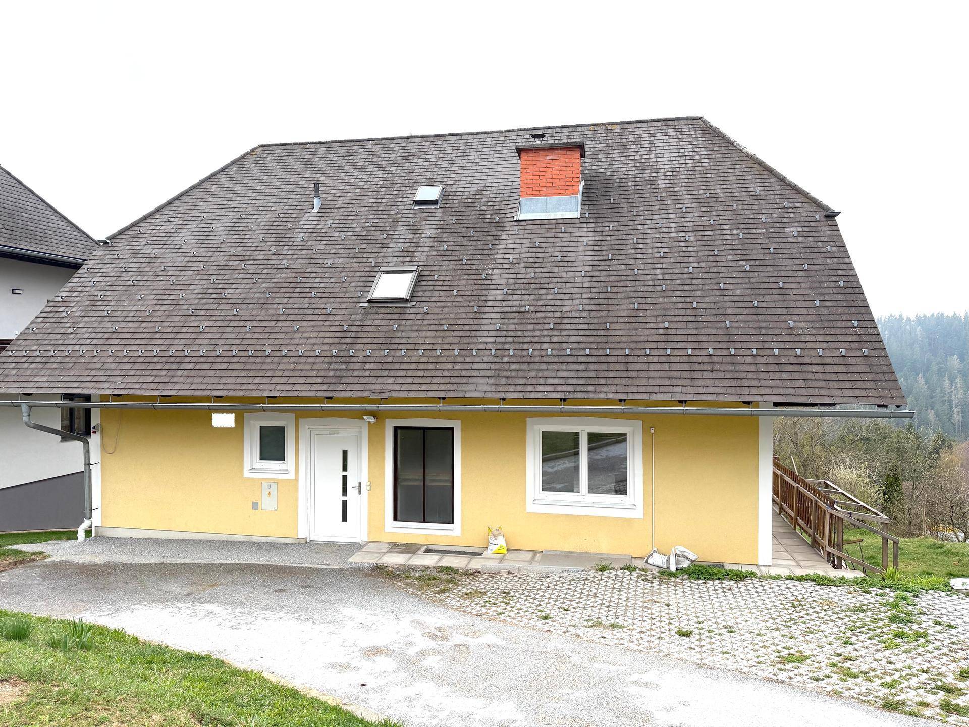 Rückansicht des Hauses mit gelber Fassade, Satteldach und gepflegtem Außenbereich.