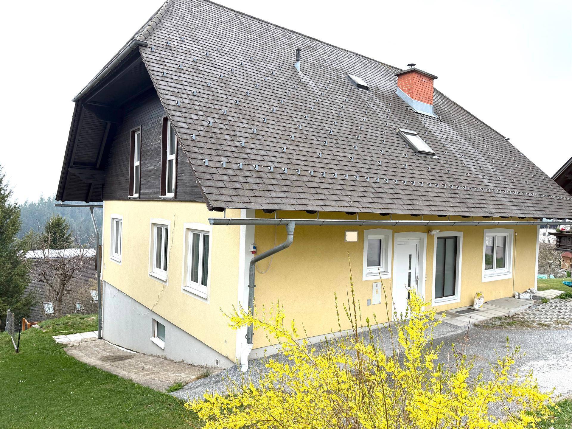 Vorderansicht des Hauses mit gelber Fassade, weißer Eingangstür und gepflegtem Vorgarten.