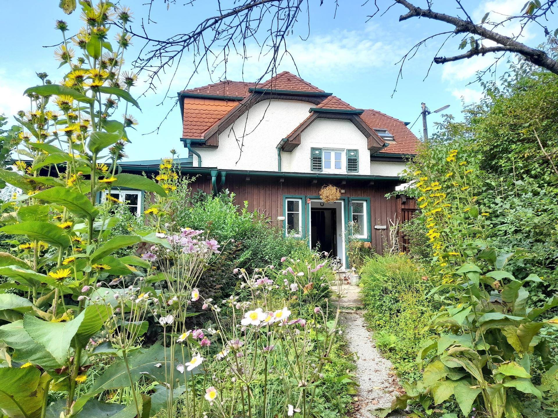 Einladendes Landhaus mit blühendem Vorgarten und einem charmanten Weg zum Hauseingang.