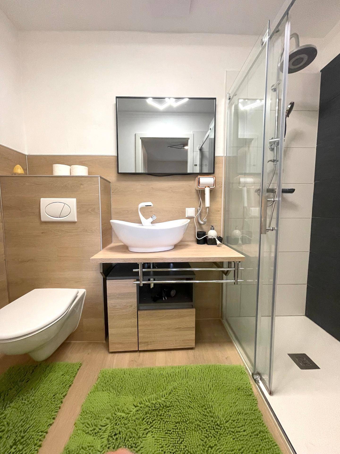 Ein modernes Badezimmer mit begehbarer Dusche, schwebendem Waschtisch und Holzdetails.