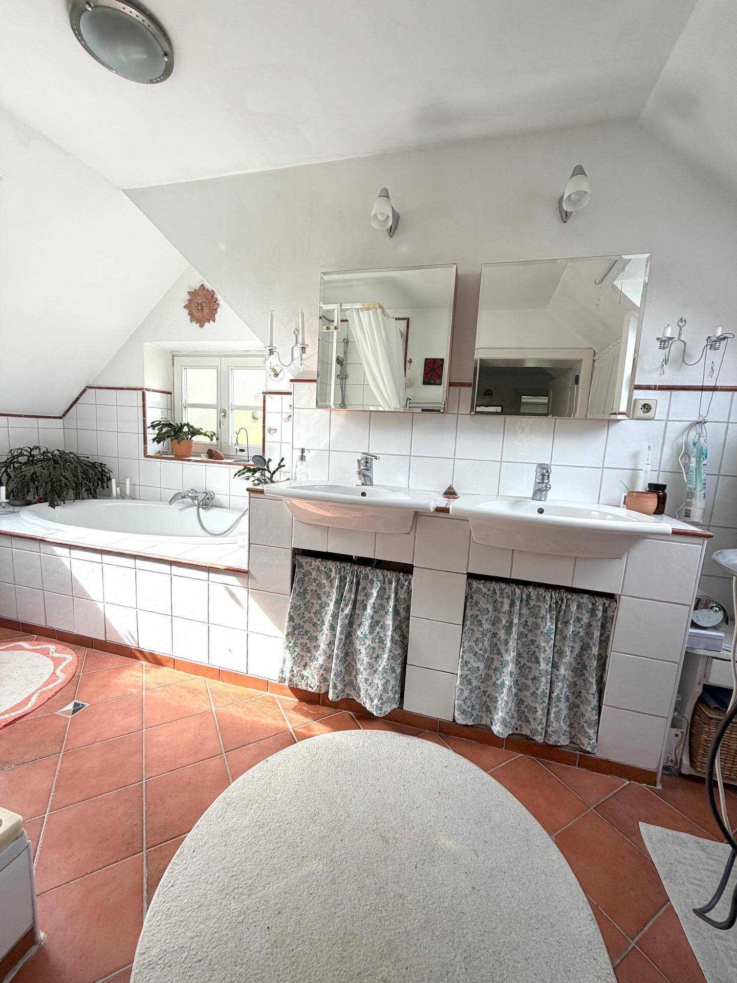 Geräumiges Badezimmer im Dachgeschoss mit Doppelwaschbecken, Badewanne und Fliesenboden.