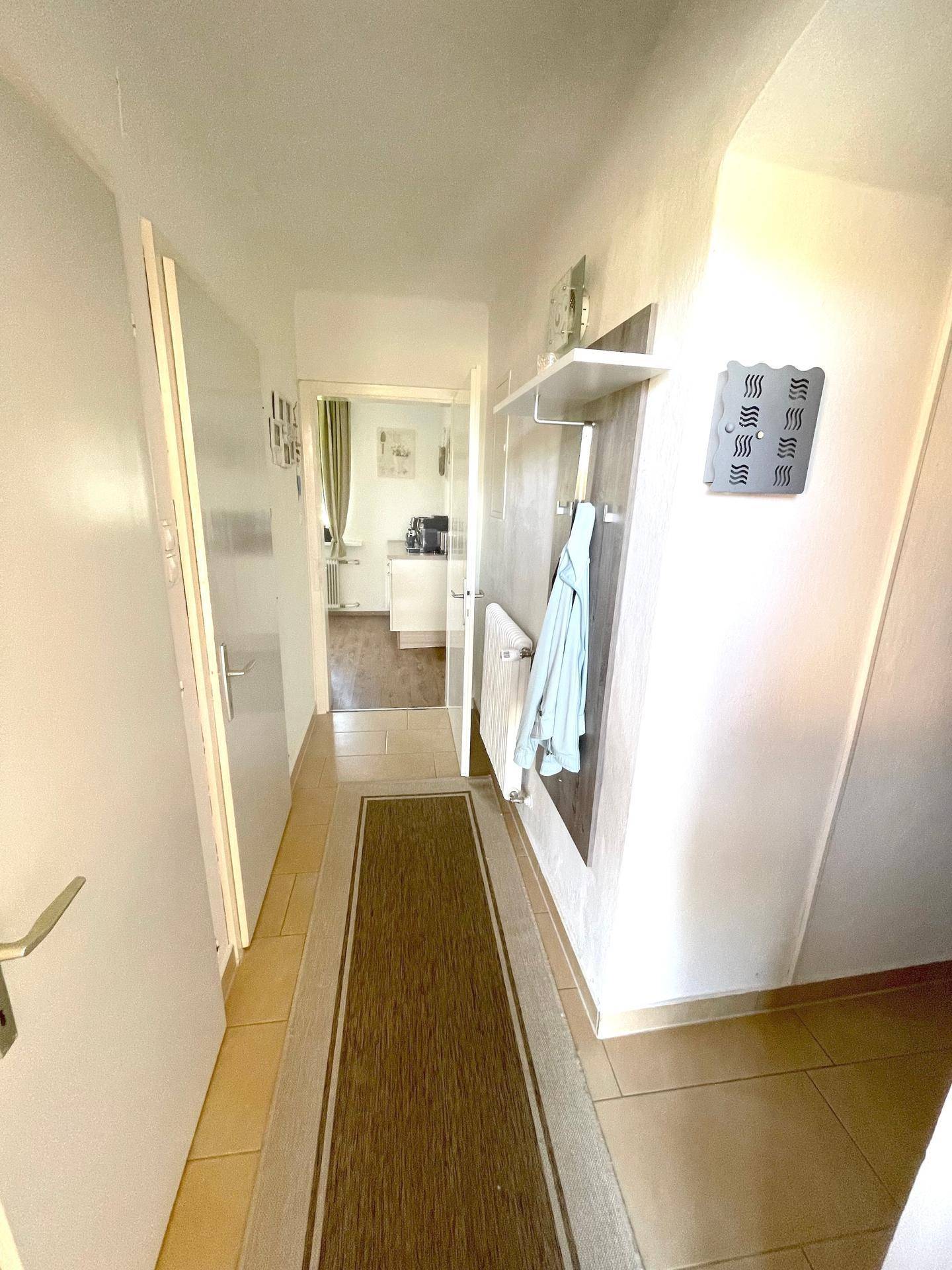 Heller Flur mit Garderobe, Teppichläufer und Blick in die moderne Küche.