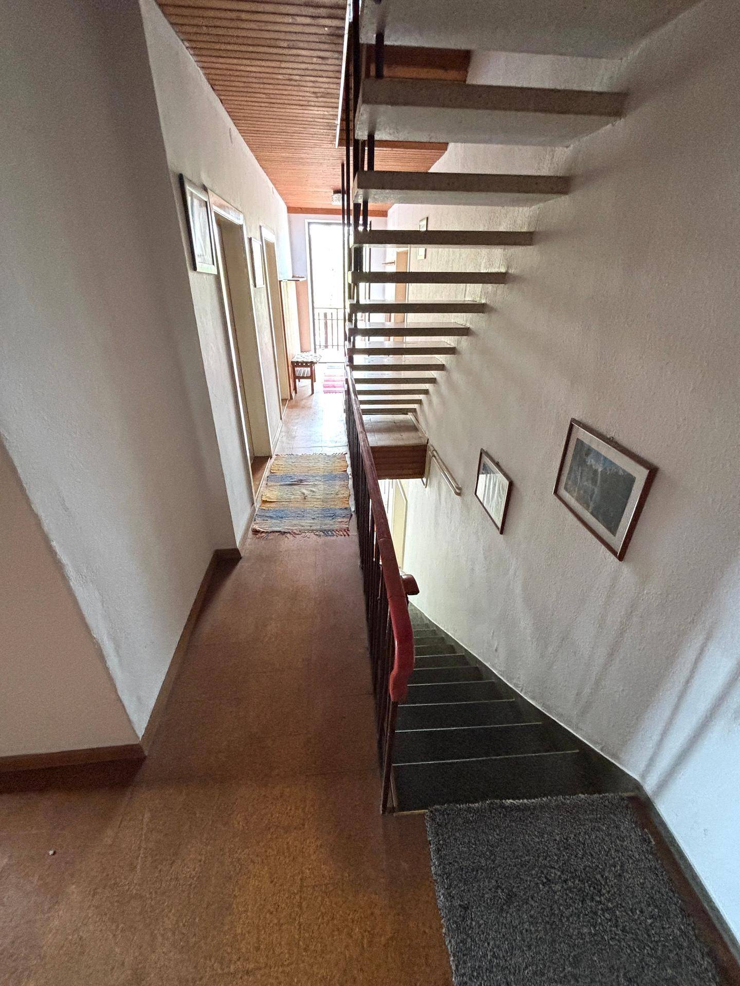 Langer Flur im Obergeschoss mit Holzdecke und Teppichläufern.