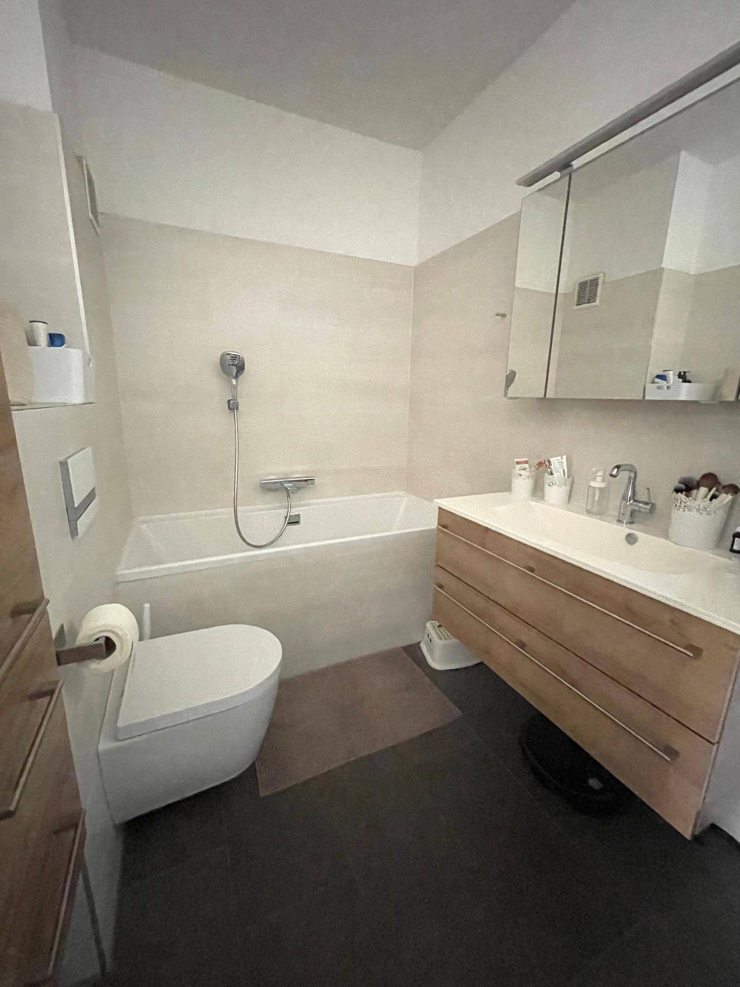 Modernes Badezimmer mit Badewanne, Waschtisch und Wand-WC.