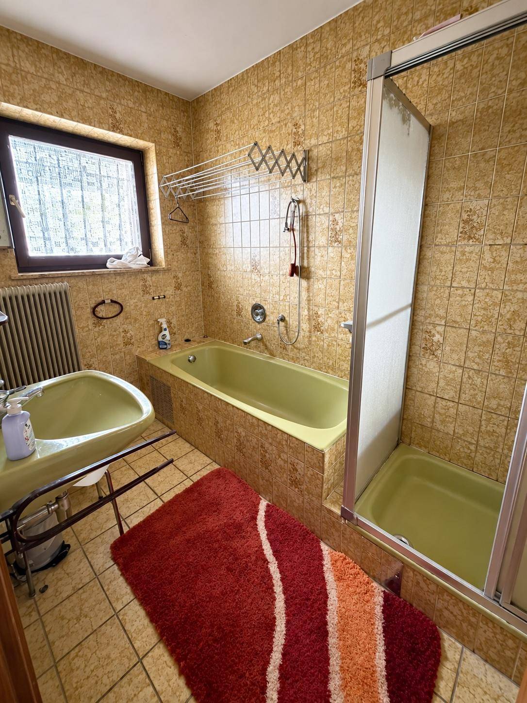 Badezimmer mit grüner Badewanne, Dusche und Fliesen im Retro-Stil.