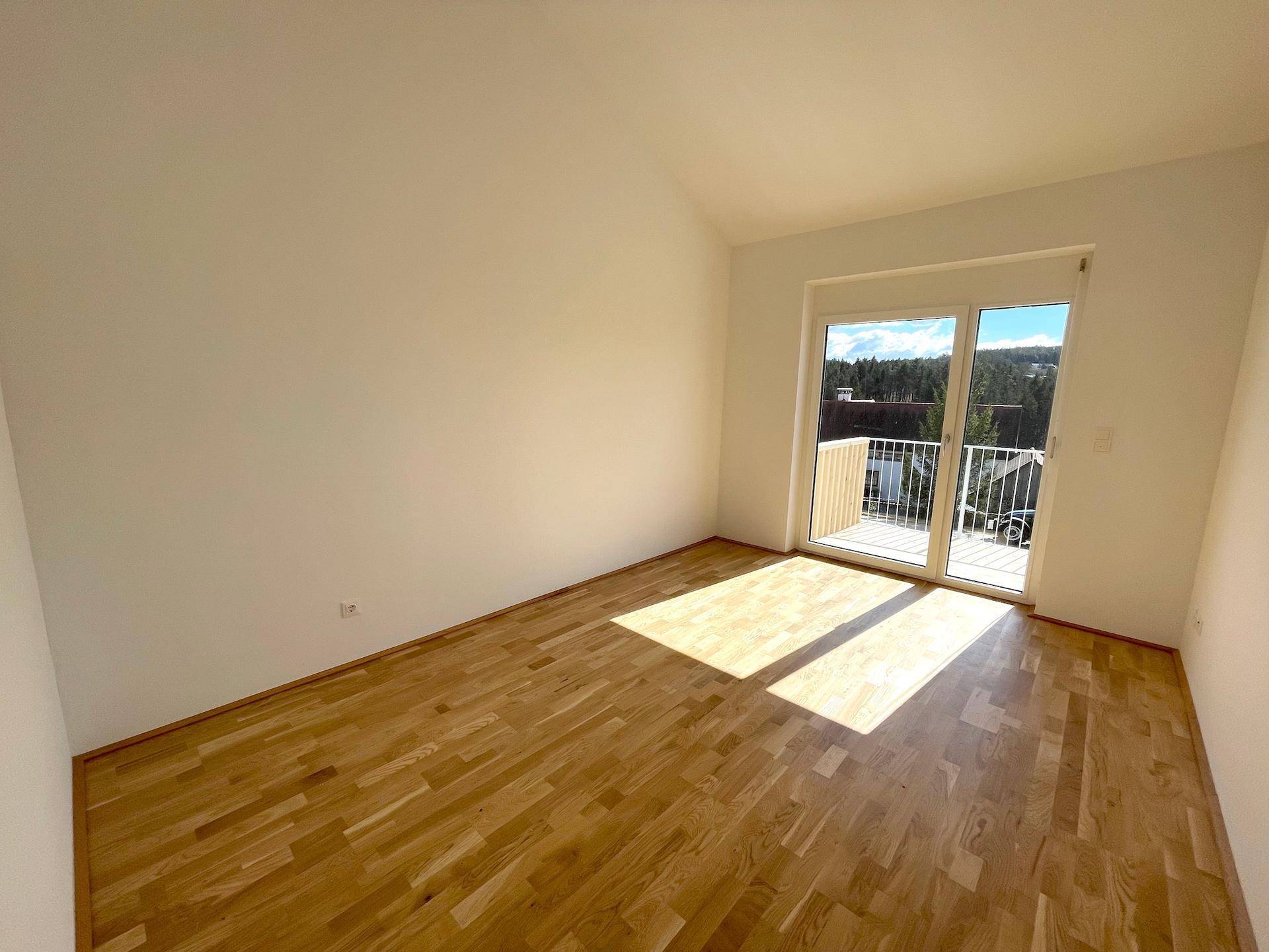 Sonniger Raum mit Holzboden und Balkonzugang, ideal als Schlafzimmer oder Büro.
