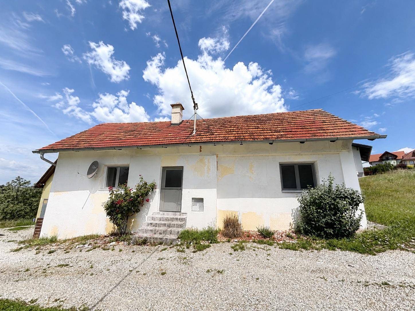 Vorderansicht des älteren Hauses mit Eingangsbereich und leicht abblätternder Fassade.