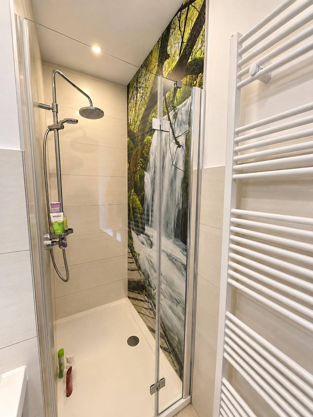Geräumige Duschkabine mit Regendusche und dekorativer Wandgestaltung, modern und hell.