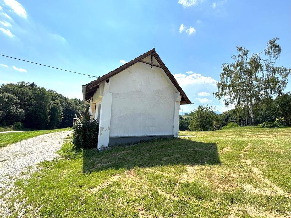 Seitenansicht des kleinen, älteren Hauses mit weißer Fassade und rotem Ziegeldach.