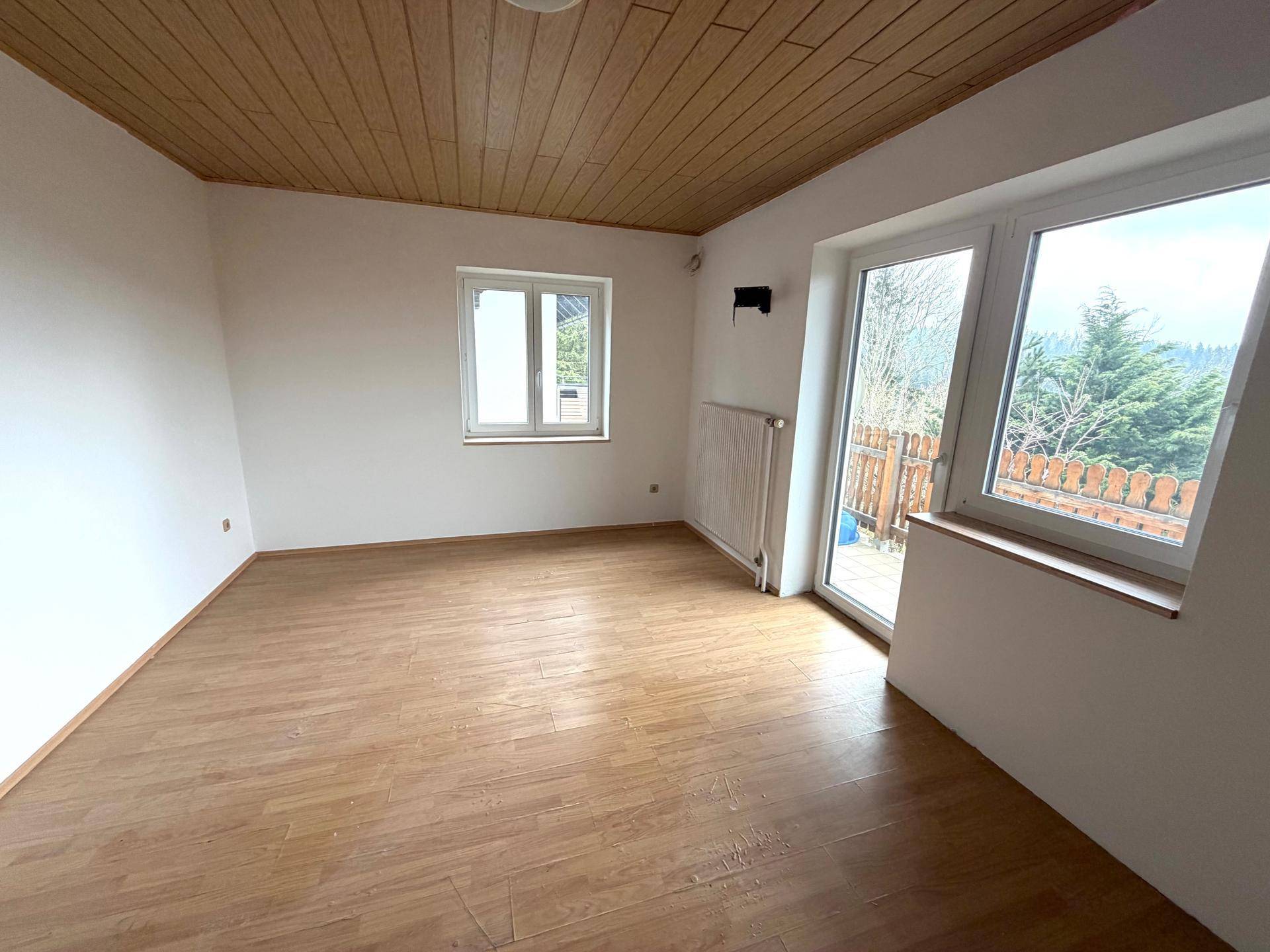 Freundliches Zimmer mit Holzdecke, Laminatboden und viel Tageslicht, bietet eine angenehme Atmosphäre.