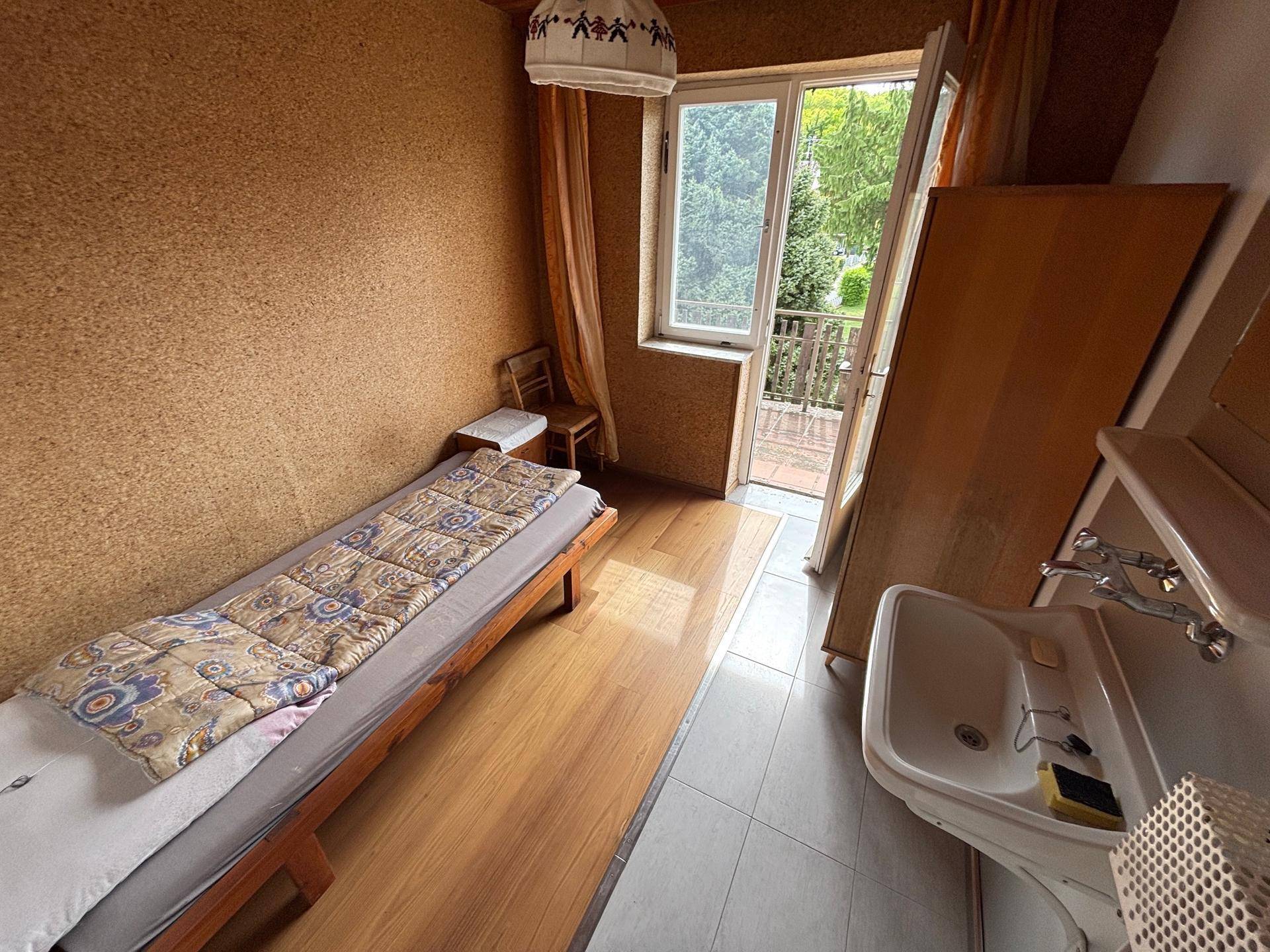 Schlafzimmer mit Korkwänden, Holzboden und Zugang zu einem Balkon.