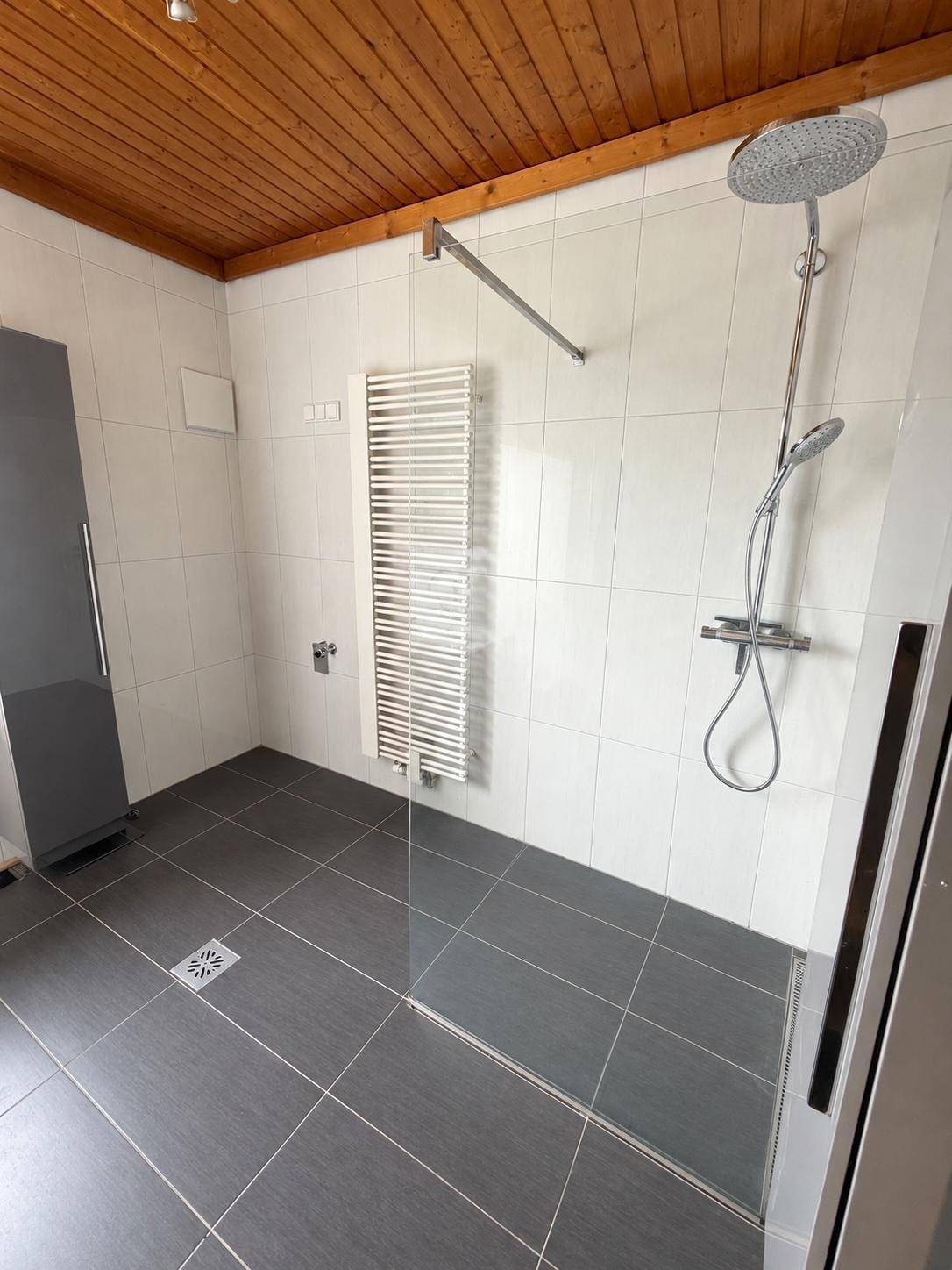 Modernes Badezimmer mit ebenerdiger Dusche, Regendusche und Handtuchheizkörper.