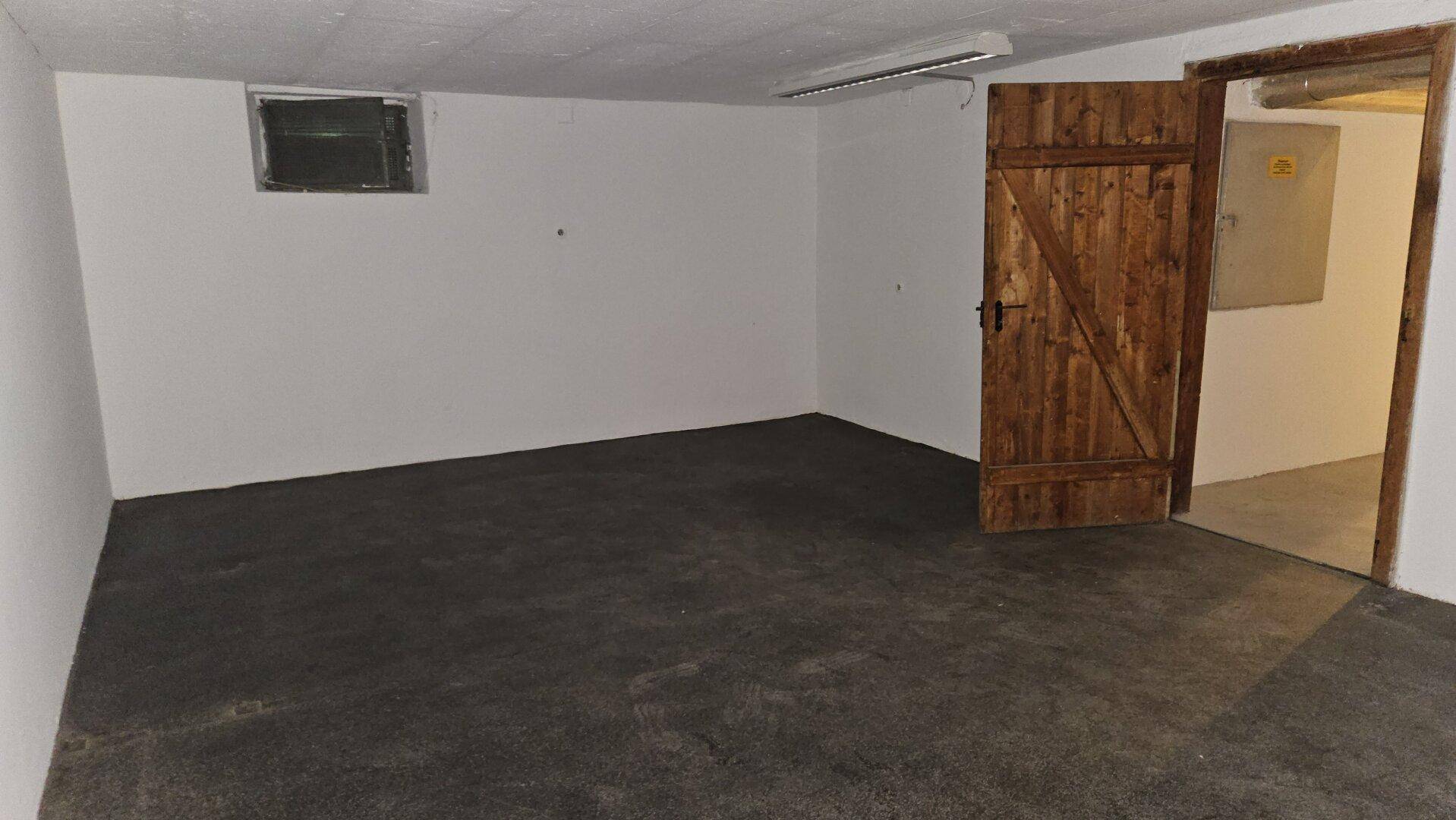 Geräumiger Kellerraum mit Betonboden, weißen Wänden und kleinem Fenster.