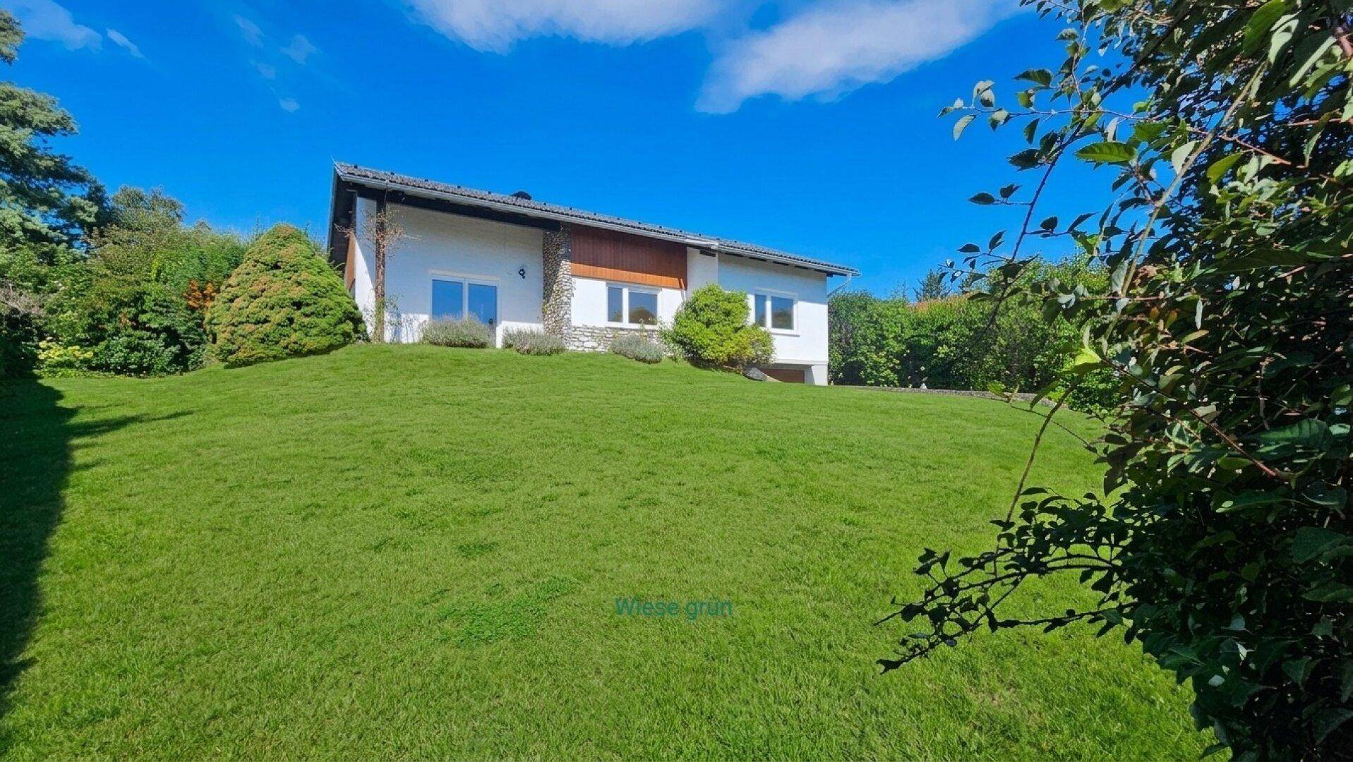 Gepflegtes Einfamilienhaus mit weitläufigem, grünem Rasen und sonniger Hanglage.