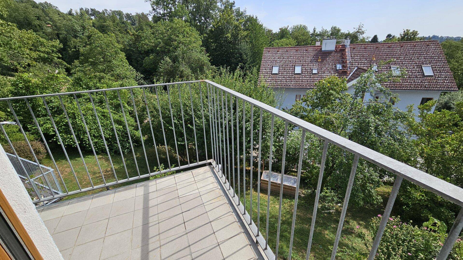 Balkon mit Fliesenboden und Metallgeländer, bietet einen ruhigen Blick in den Garten.
