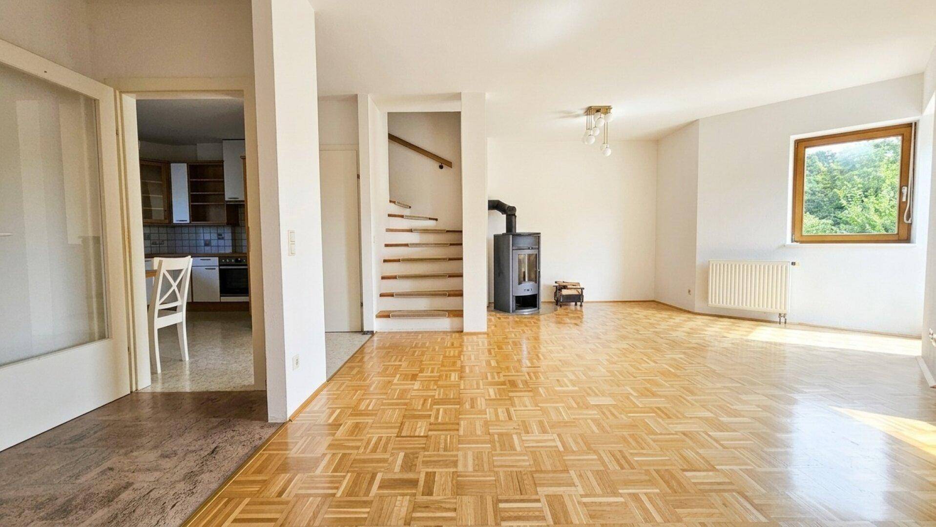 Geräumiges Wohnzimmer mit Parkettboden, Kaminofen und direktem Zugang zur Küche.