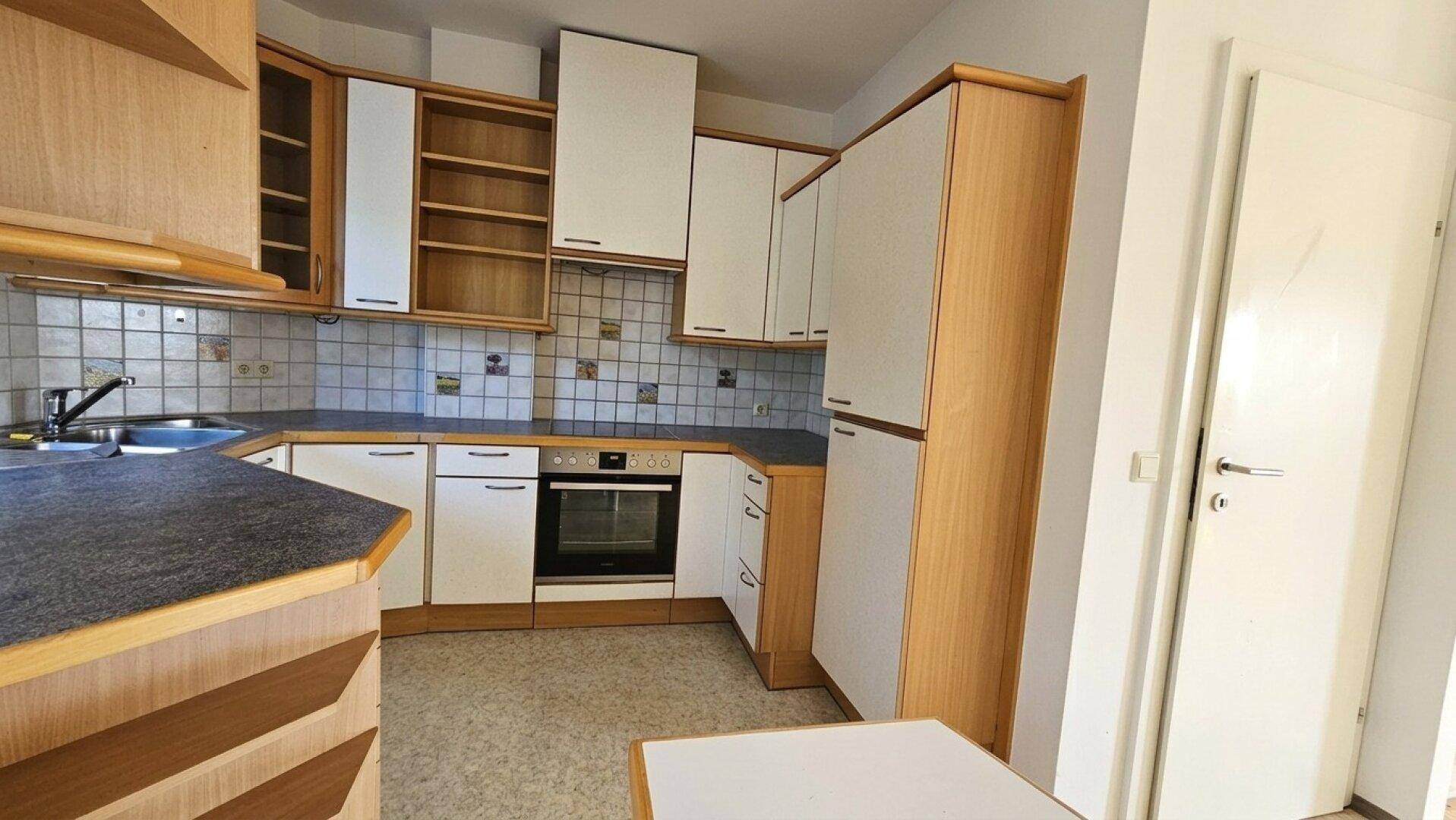 Funktionale Küche mit Holzschränken, weißen Fronten und integrierten Geräten.