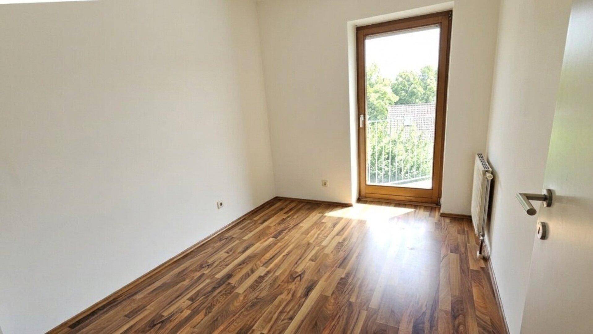 Kleineres Zimmer mit Laminatboden und Zugang zu einem französischen Balkon, ideal als Kinderzimmer.