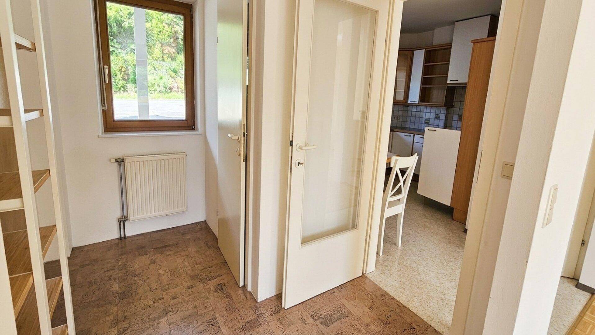 Flur mit Korkboden und Fenster, der zur Küche führt und viel Licht bietet.