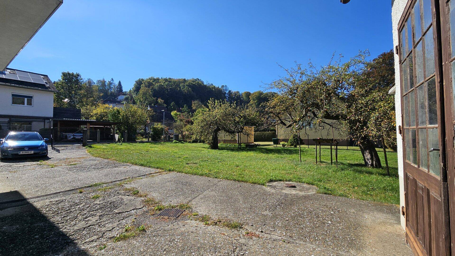 Großer Hofbereich mit Rasenfläche, Obstbäumen und Blick auf die umliegende Landschaft.