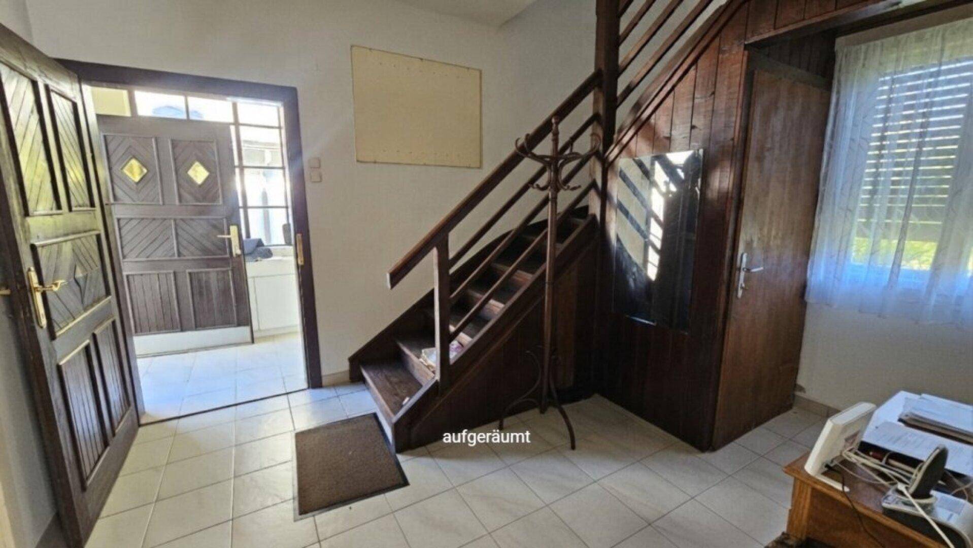 Eingangsbereich mit gefliestem Boden, Holztreppe und Holztüren im traditionellen Stil.