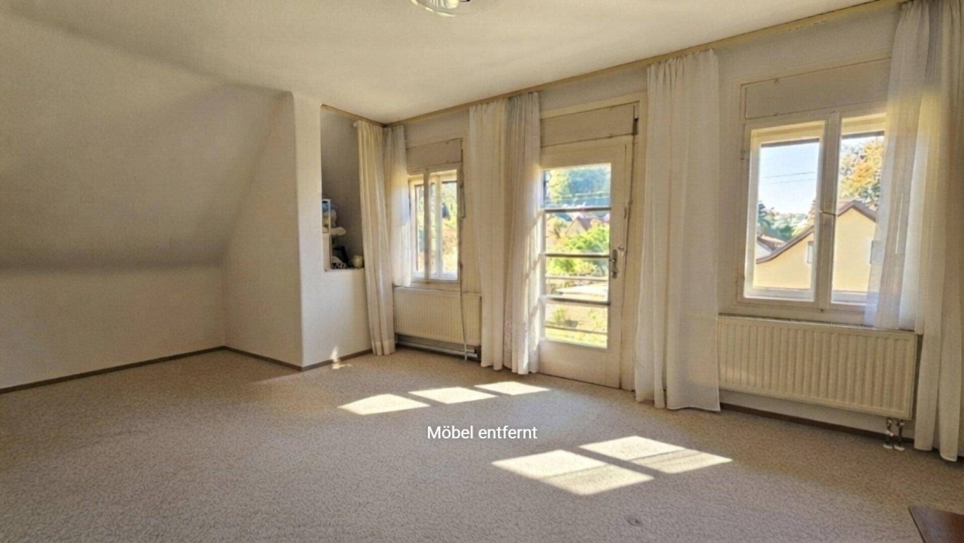 Helles Zimmer mit Teppichboden, Dachschräge und Zugang zu einem französischen Balkon.