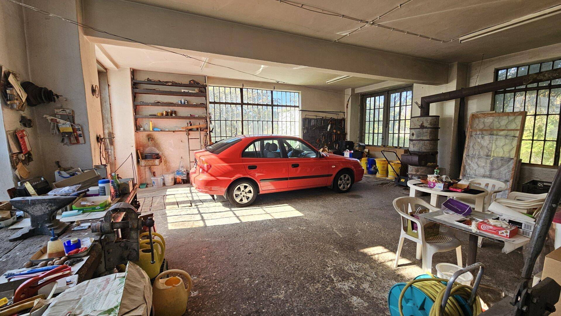 Geräumige Garage mit Betonboden, Werkstattbereich und großen Fenstern.