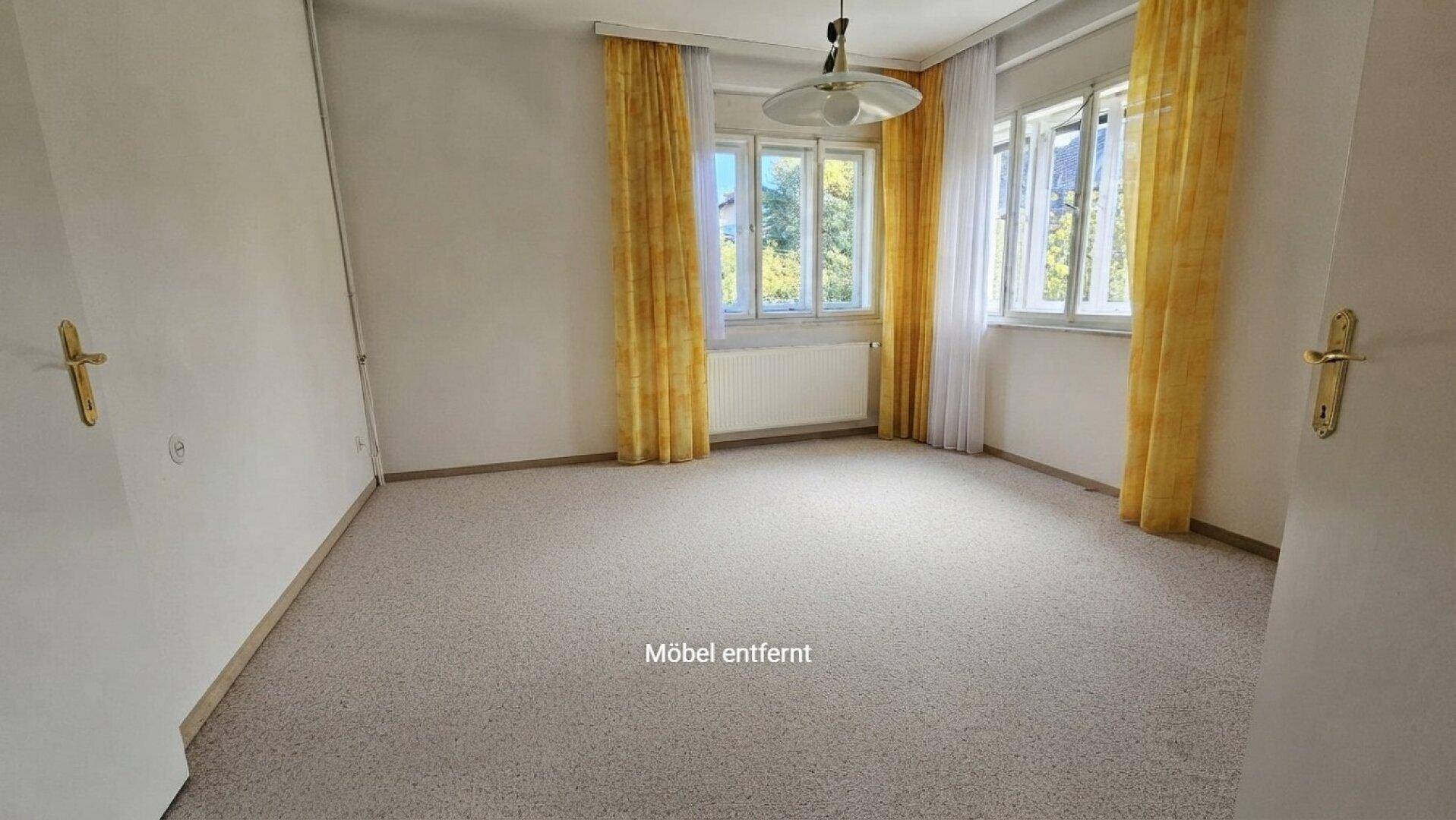 Geräumiges Zimmer mit hellem Teppichboden und großen Fenstern, die viel Tageslicht hereinlassen.