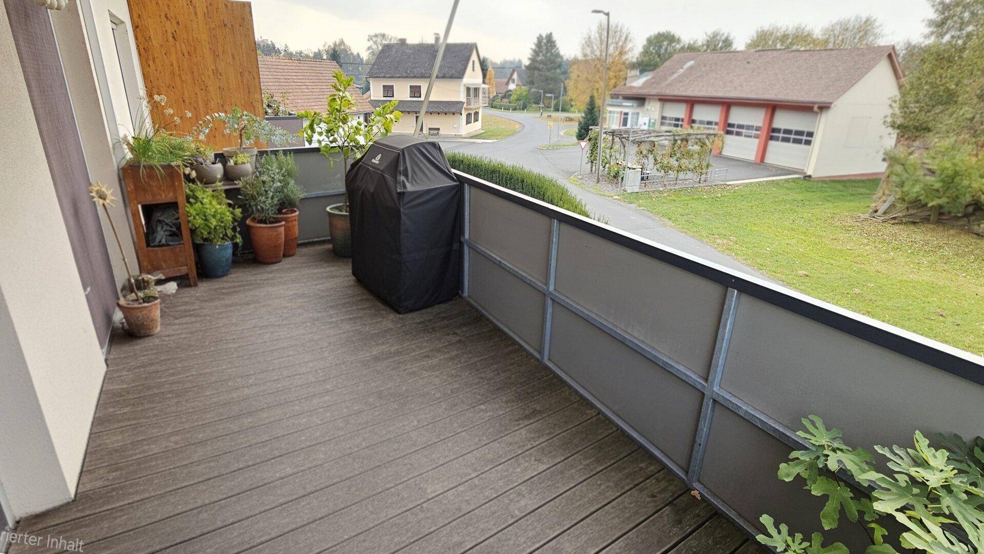 Balkon mit Grill und Pflanzen, bietet einen Blick auf die umliegende Straße.