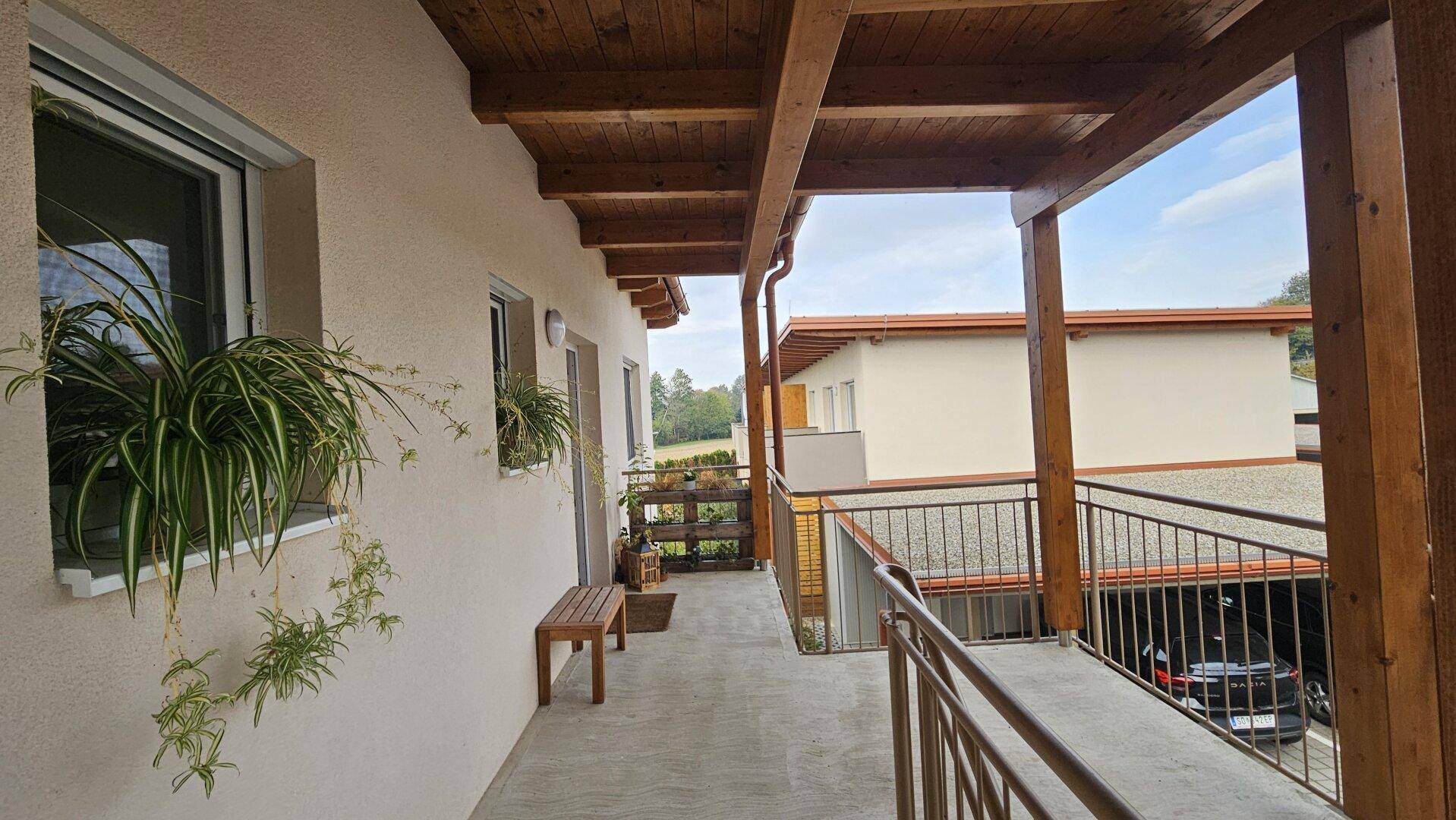 Langer überdachter Balkon mit Holzdach und Metallgeländer, ideal zum Entspannen.