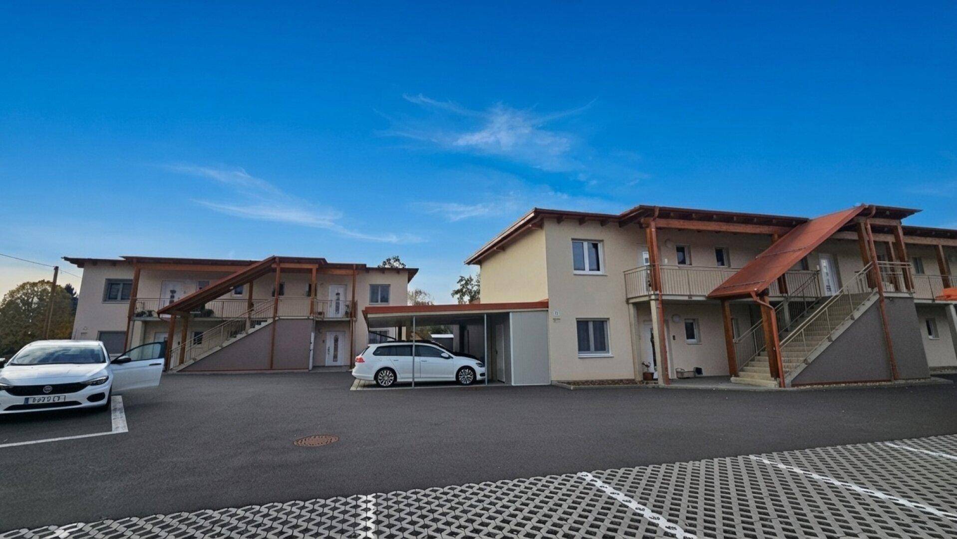 Neubau-Wohnanlage mit mehreren Gebäuden, Carports und ausreichend Parkplätzen.