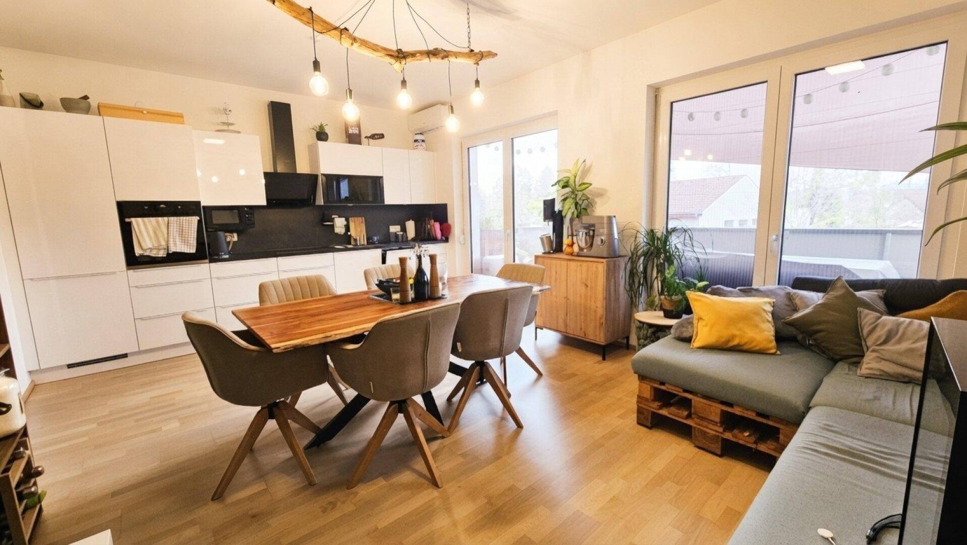 Heller offener Wohn-Essbereich mit moderner Küche und Zugang zur Terrasse.