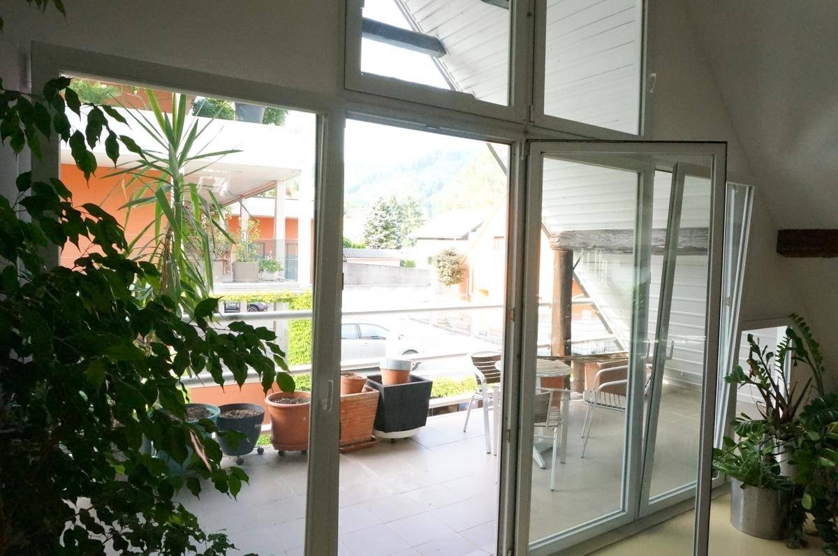 Balkon mit Pflanzen und Blick auf die Umgebung, zugänglich durch große Glasfenster.