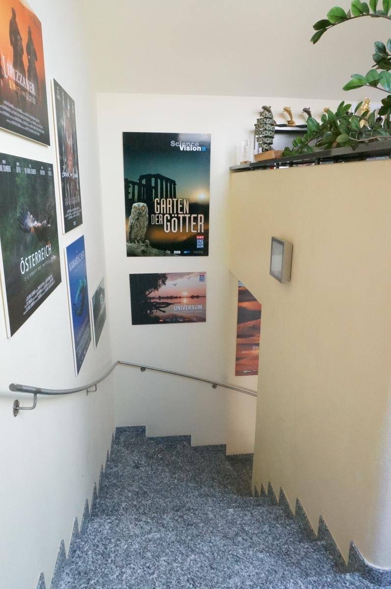 Treppenhaus mit Granitstufen und Handlauf, dekoriert mit Postern an den Wänden.