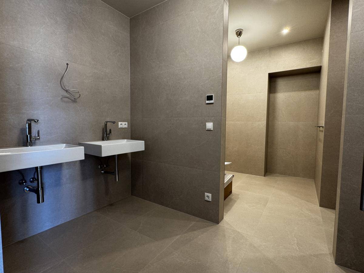 Modernes Badezimmer mit zwei Waschbecken und großformatigen grauen Fliesen, bietet viel Platz.