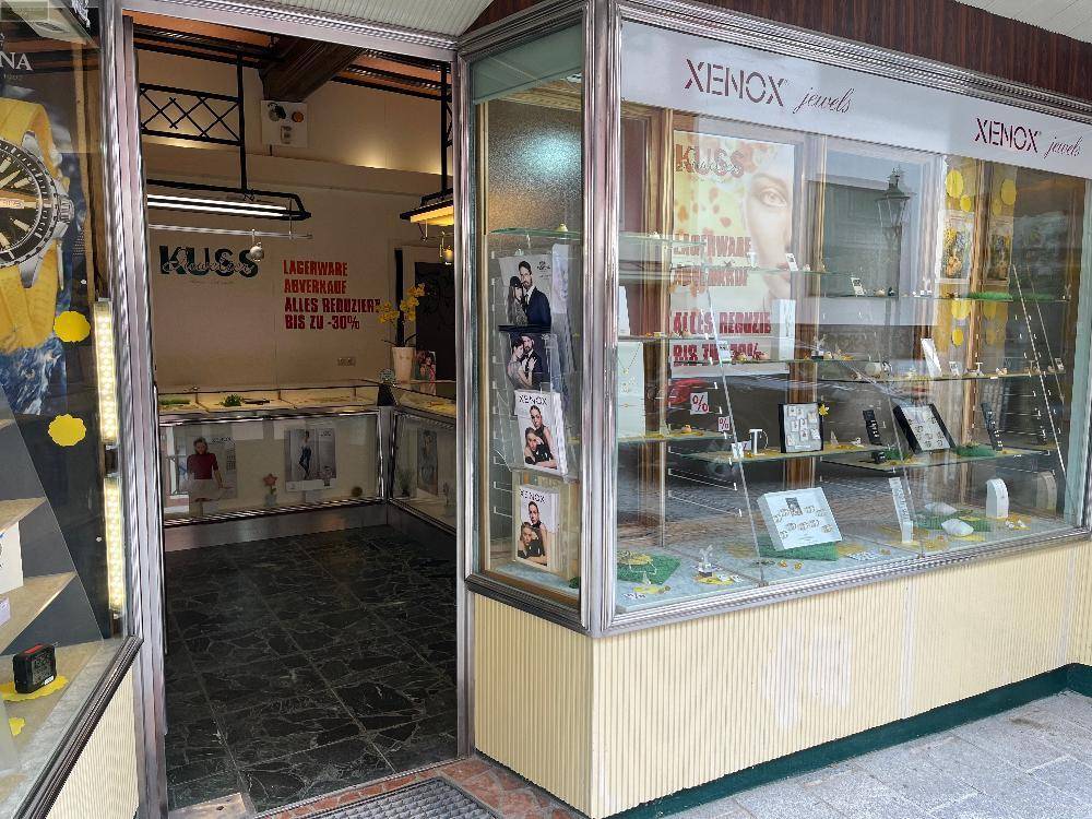 Innenansicht eines Juweliergeschäfts mit Auslagen und einem Eingangsbereich, der zum Verkaufsraum führt.