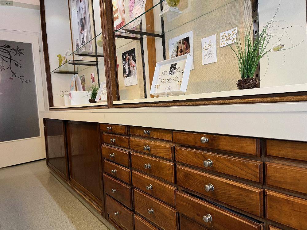 Detailansicht von Holzschubladen und einer Verkaufstheke in einem traditionellen Juweliergeschäft.