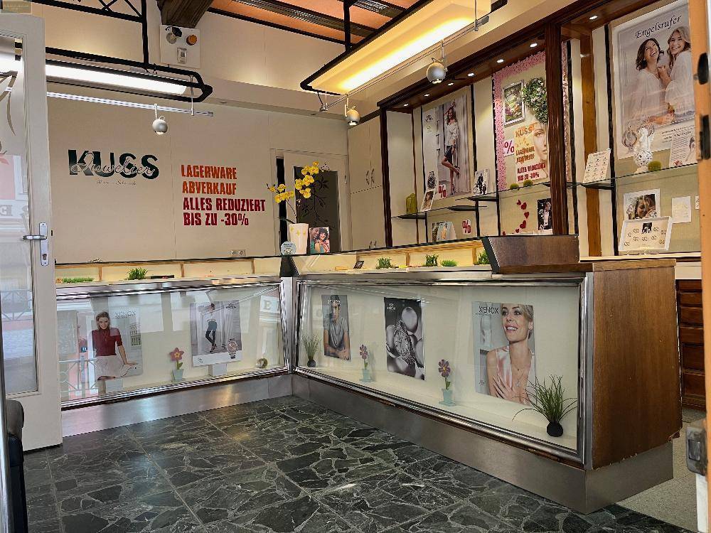 Innenansicht eines Juweliergeschäfts mit Verkaufstheken und Auslagen für Schmuck und Uhren.