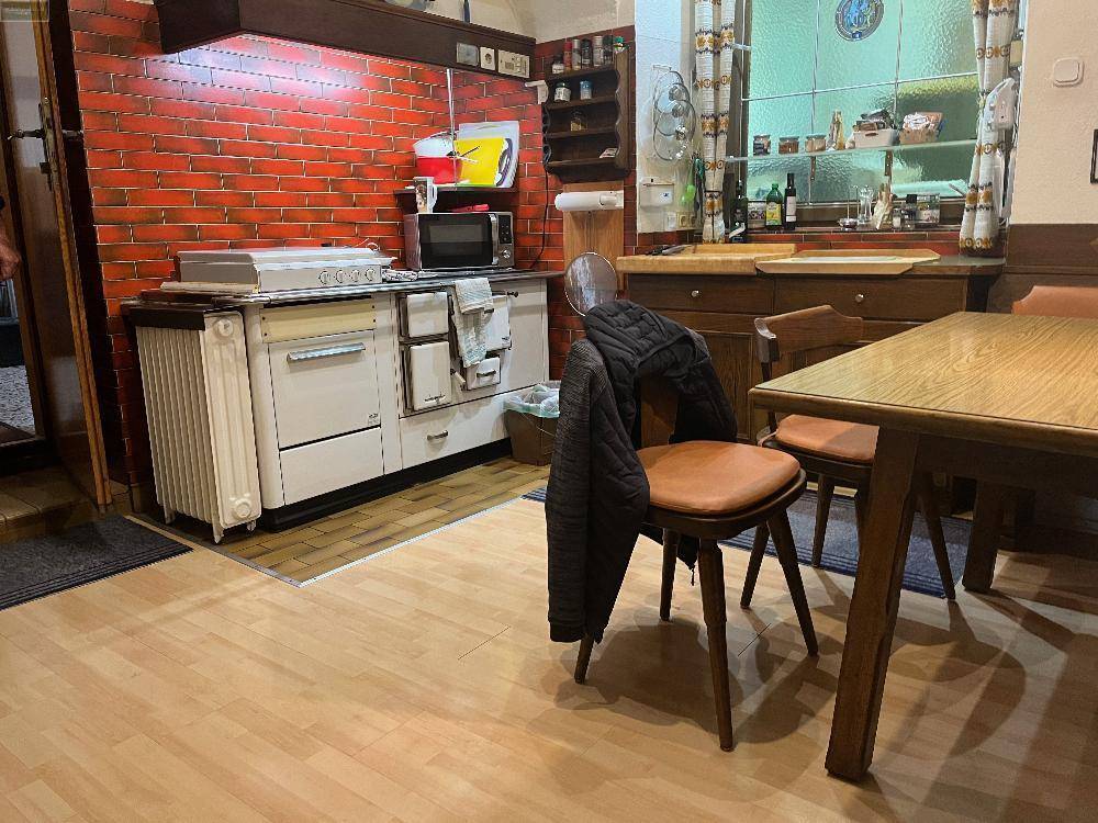 Rustikale Küche mit traditionellem Holzherd, Backsteinwand und hellem Holzboden, ideal für gemütliche Mahlzeiten.