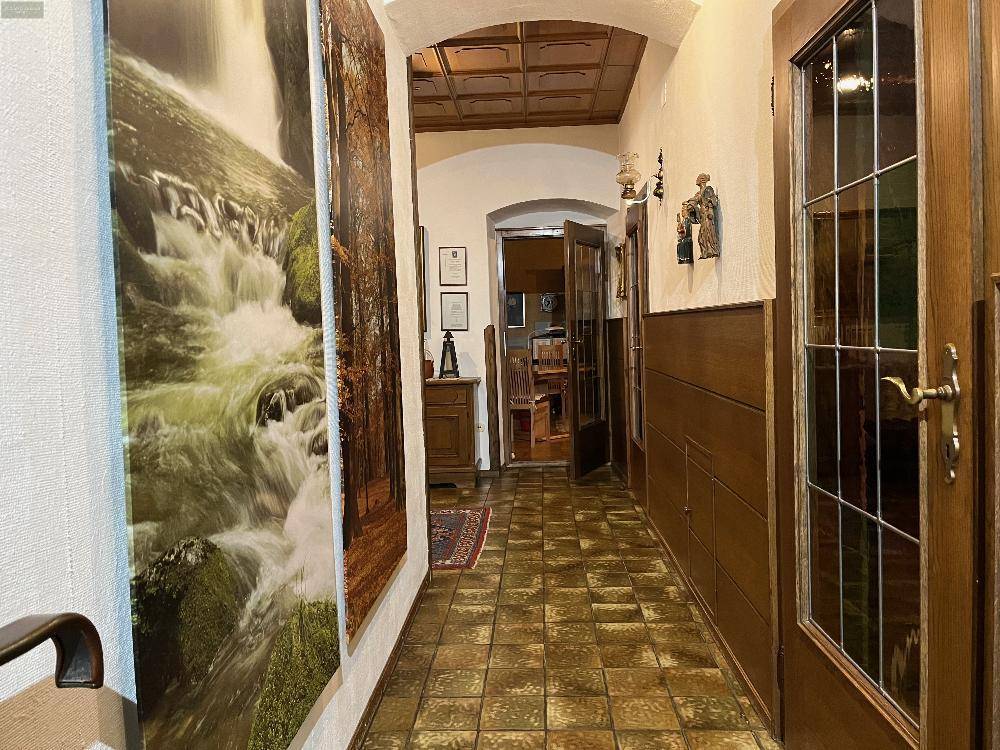 Langer Flur mit Fliesenboden, Holzvertäfelung und traditioneller Deckenverkleidung, führt zu weiteren Räumen.