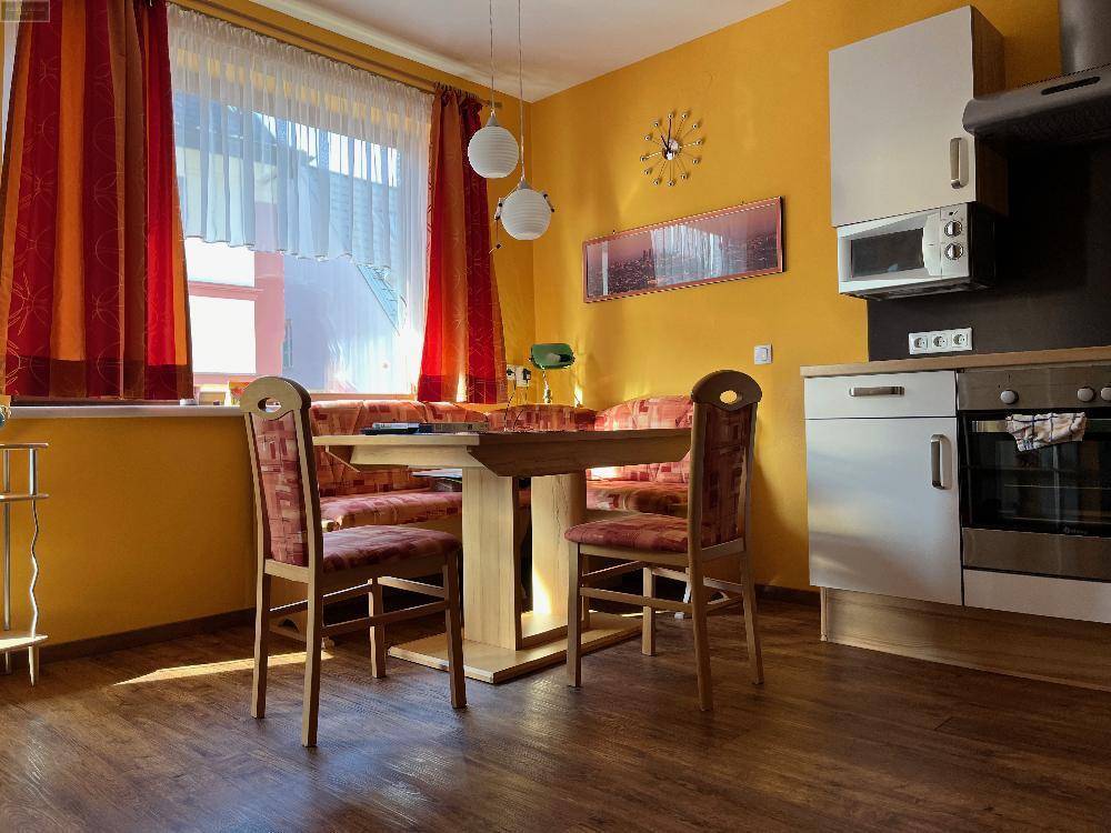 Essbereich in der Küche mit Holztisch, Eckbank und gelben Wänden, ideal für gemeinsame Mahlzeiten.